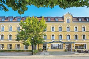 ein großes gelbes Gebäude mit einem Baum davor in der Unterkunft Hotel Liebl in Plattling