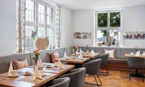 a restaurant with wooden tables and chairs and windows at Hotel Liebl in Plattling