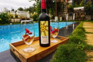 a bottle of wine and two wine glasses on a wooden tray at La Niebla Farm Resort in Ooty