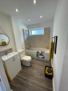a bathroom with a toilet and a sink and a tub at Quiet and central modern new build bungalow in Hereford