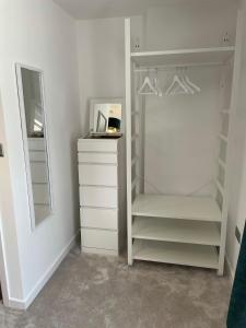 a white closet with shelves and a mirror at Quiet and central modern new build bungalow in Hereford