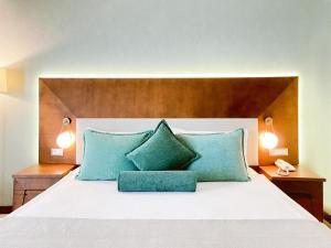 a bed with two blue pillows and two lamps at Ilica Hotel Spa & Wellness Resort in Çeşme