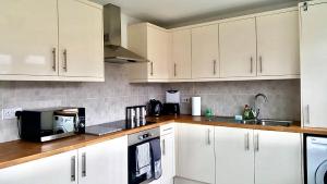 a kitchen with white cabinets and a black microwave at Property Hunter 23 in Darlington