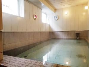 a swimming pool in a room with a clock on the wall at Hotel Onahama Hills in Iwaki