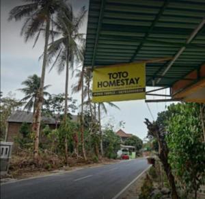 a togo honeyay sign hanging from a building on a road at Toto Homestay in Magelang