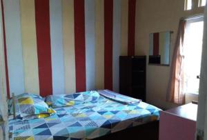 a bed in a room with a striped wall at Toto Homestay in Magelang