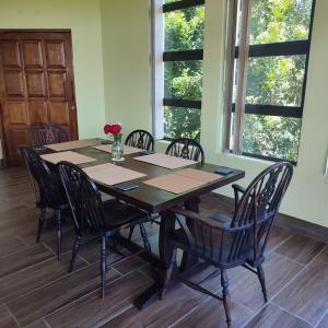 a dining room table and chairs in a room with windows at African Sunset Villa in Chintsa