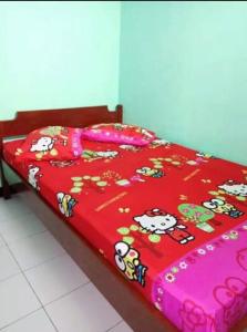 ein Bett mit einer roten Bettdecke und Cartoons drauf in der Unterkunft Hotel Teratai Putih in Baturaden