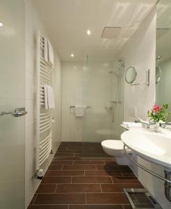 ein Badezimmer mit zwei Waschbecken, einem WC und einer Dusche in der Unterkunft Hotel Klughardt in Nürnberg