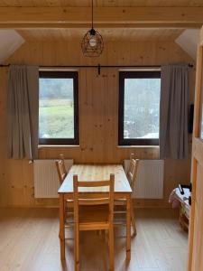 a wooden table and chairs in a room with two windows at Drevenica Humno in Terchová