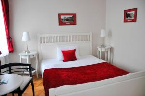 a white bedroom with a red pillow on a bed at Pivovar Hotel Na Rychtě in Ústí nad Labem