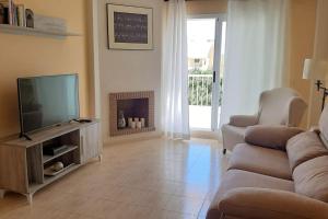 a living room with a couch and a television at Ático con terraza abierta/Open terrace apartment in Mijas