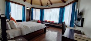 a bedroom with a bed with blue curtains and windows at Casa Himalaya, Auli in Joshīmath