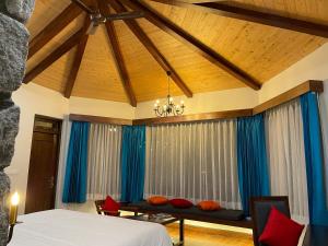 a bedroom with blue curtains and a bed and a table at Casa Himalaya, Auli in Joshīmath