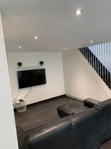 uma sala de estar com um sofá de couro preto e uma televisão em Loft Porte de Gentilly em Gentilly