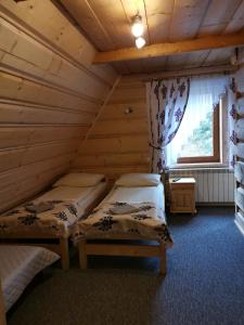 1 dormitorio con 2 camas en una cabaña de madera en Pokoje gościnne Pod Limbami, en Małe Ciche