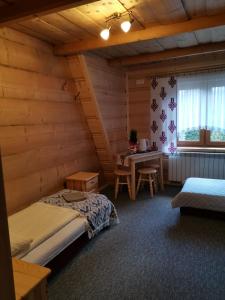 1 dormitorio en una cabaña de madera con cama y escritorio en Pokoje gościnne Pod Limbami, en Małe Ciche