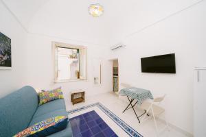 Una sala de estar con un sofá azul y un televisor. en Nonna Titti, en Amalfi