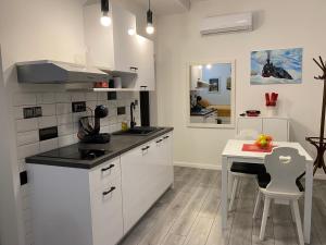 a kitchen with white cabinets and a white table and a table and a dining room at Studio Apartman Lora in Lipik