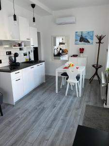 a kitchen with white cabinets and a white table and chairs at Studio Apartman Lora in Lipik