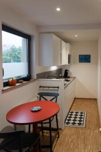 kuchnia z czerwonym stołem i krzesłami oraz oknem w obiekcie Studio Les Terrasses de Kerangall w mieście Brest