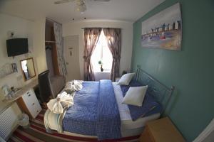 a bedroom with a bed with blue sheets and a window at The Eastleigh in Skegness