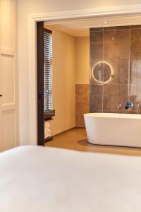 een badkamer met een wit bad en een wastafel bij The Yard hotel Zuidkade in Veghel