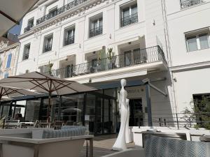 ein weißes Gebäude mit einer Statue davor in der Unterkunft Hôtel Le Canberra in Cannes