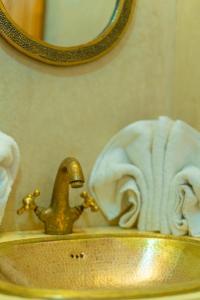 a bathroom sink with a gold faucet and a towel at Riad Louaya in Marrakech