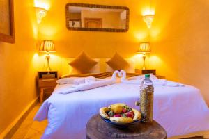 - une chambre avec un lit et une corbeille de fruits sur une table dans l'établissement Riad Louaya, à Marrakech