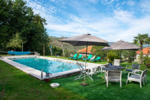 a swimming pool with two umbrellas and a table and chairs at Quinta da Quinta in Vieira do Minho