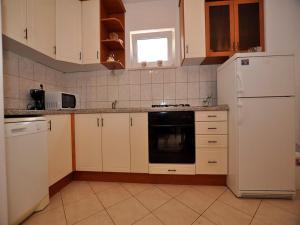 a kitchen with white cabinets and a black dishwasher at Apartments Seagull in Postira