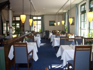 un comedor con mesas y sillas blancas y ventanas en Pension und Schänke Lenzer Krug, en Lenz