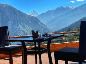 a table with two chairs and a view of mountains at Casa Himalaya, Auli in Joshīmath