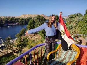 a woman standing on a rail holding a flag at El Prince Guesthouse in Aswan