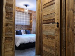 a bedroom with a bed and a wooden wall at Ecrin des Glaciers Combloux in Combloux