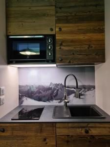 a kitchen with a sink and a microwave at Ecrin des Glaciers Combloux in Combloux