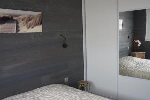 ベルク・シュル・メールにあるLe Grand Largeの木のアクセントの壁とベッドが備わるベッドルーム1室が備わります。