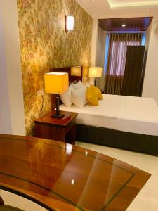 Habitación de hotel con cama y mesa con lámpara en ruwanara royal majestry en Ambagahagedara