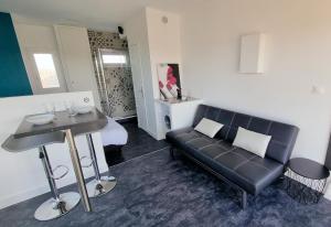 a living room with a black couch and a table at Cyrène Port Nature 5 in Cap d'Agde