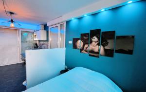 een slaapkamer met een blauwe muur met foto's van een vrouw bij Cyrène Port Nature 5 in Cap d'Agde
