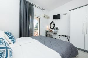 a bedroom with a white bed and a sliding glass door at Garden Studios Thassos Town in Limenas