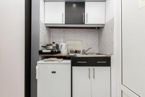 a white kitchen with white cabinets and a sink at Garden Studios Thassos Town in Limenas