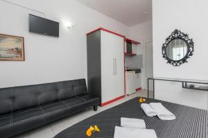 a living room with a black couch and a mirror at Garden Studios Thassos Town in Limenas