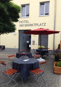 a table with chairs and an umbrella in front of a building at Hotel am Marktplatz in Gangkofen
