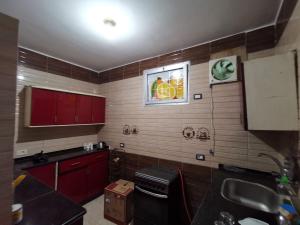 a small kitchen with red cabinets and a sink at Qussier sea view apartment in Quseir