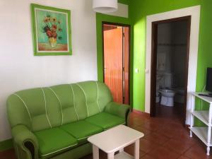 a living room with a green couch and a table at Camping Villa Park Zambujeira do Mar in Zambujeira do Mar