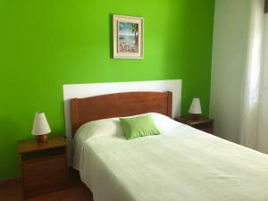 a green bedroom with a bed and two nightstands with lamps at Camping Villa Park Zambujeira do Mar in Zambujeira do Mar
