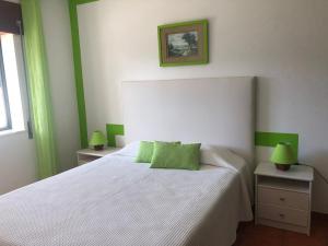 a bedroom with a white bed with green accents at Camping Villa Park Zambujeira do Mar in Zambujeira do Mar