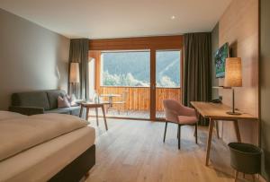 una camera d'albergo con letto, scrivania e soggiorno di TRAUBE BRAZ Alpen Spa Golf Hotel a Bludenz
